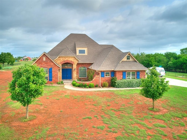 view of front of home with brick siding, a front yard, and roof with shingles