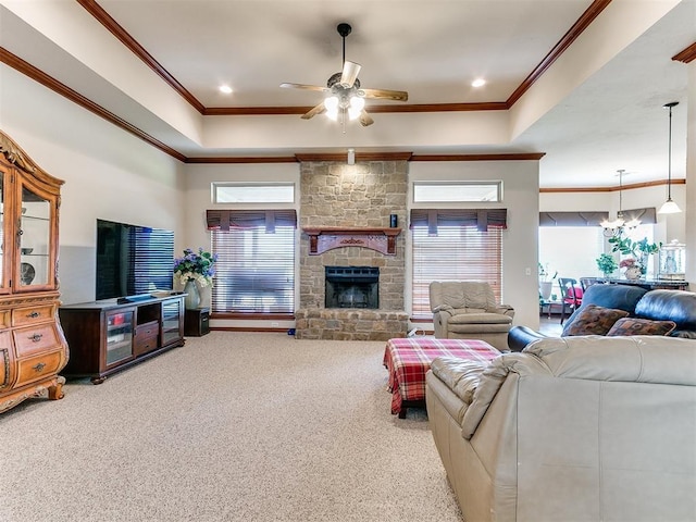living room featuring ornamental molding, carpet, a stone fireplace, and ceiling fan