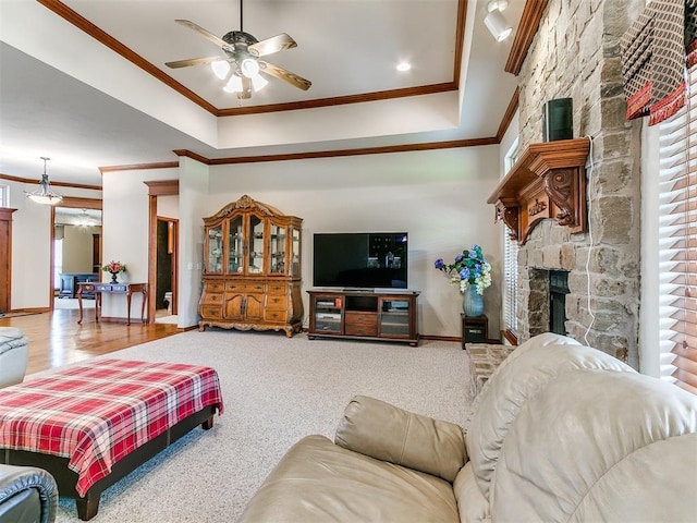 living room featuring baseboards, ornamental molding, a ceiling fan, and a stone fireplace