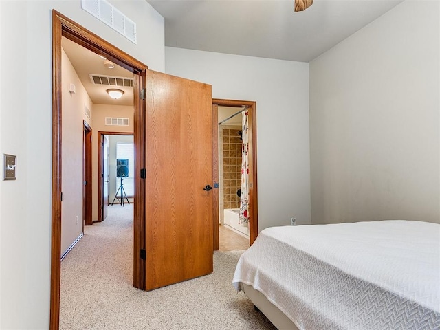 bedroom featuring visible vents, light carpet, and ensuite bath