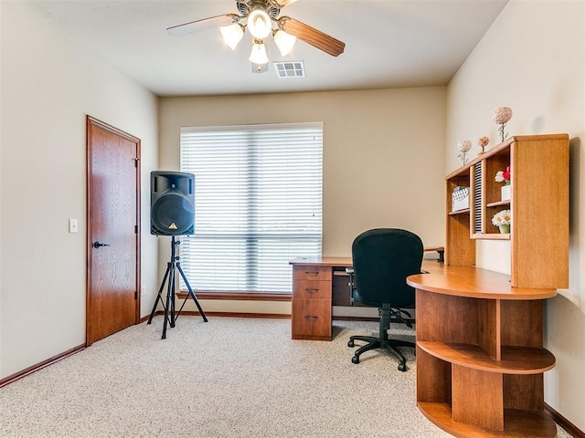 carpeted office space featuring visible vents, a ceiling fan, baseboards, and plenty of natural light