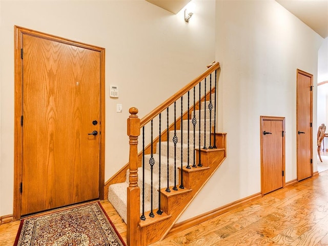 entrance foyer featuring baseboards, a high ceiling, stairs, and wood finished floors