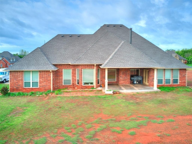 rear view of property with brick siding, a patio area, and roof with shingles
