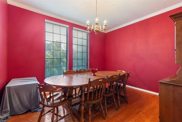 dining space featuring crown molding, baseboards, wood finished floors, and a chandelier