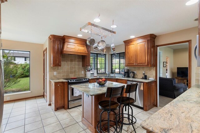 kitchen featuring custom exhaust hood, a sink, backsplash, light tile patterned floors, and stainless steel appliances
