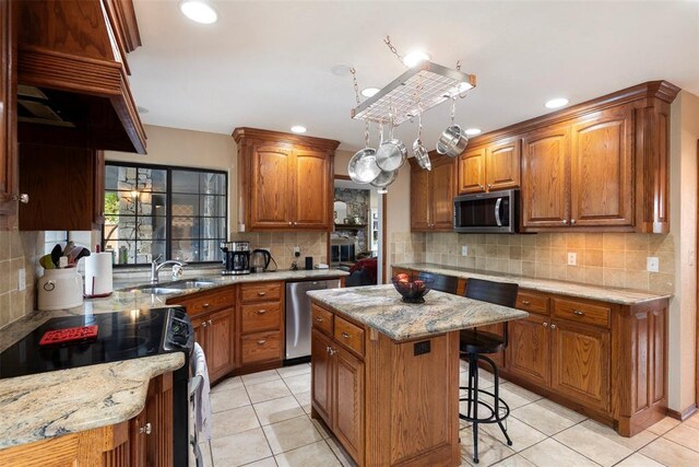 kitchen featuring decorative backsplash, light stone counters, a sink, light tile patterned floors, and stainless steel appliances