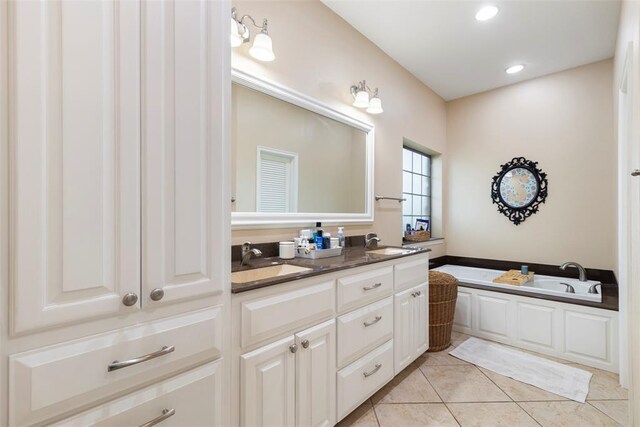bathroom with double vanity, a sink, a bath, and tile patterned floors