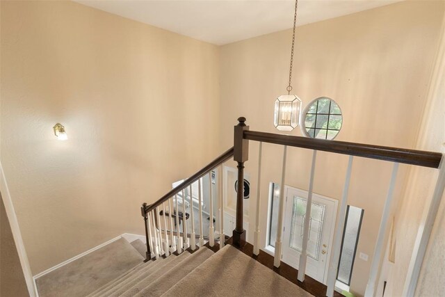 stairway with baseboards, carpet, a towering ceiling, and a chandelier