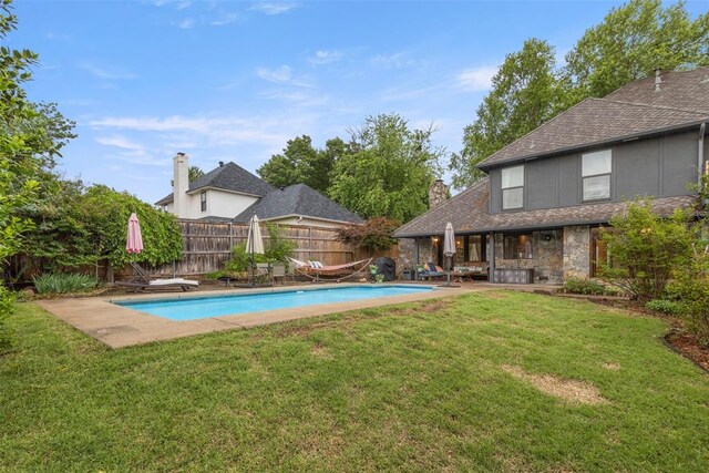 view of swimming pool with a lawn, a fenced in pool, a fenced backyard, and a patio area