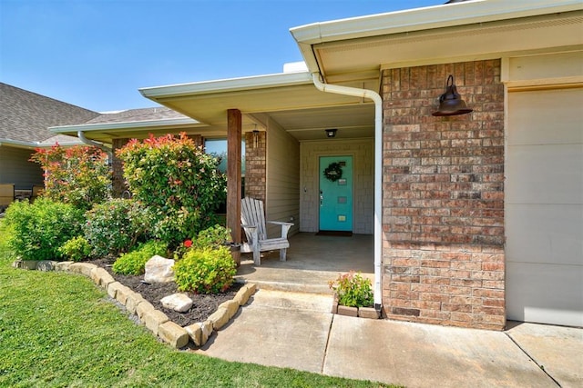 view of exterior entry featuring a porch and brick siding