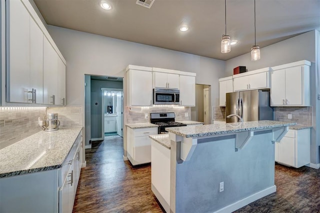 kitchen featuring dark wood-style flooring, an island with sink, backsplash, and stainless steel appliances