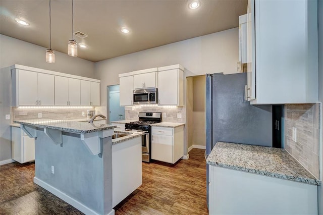 kitchen featuring a sink, appliances with stainless steel finishes, a breakfast bar, and backsplash
