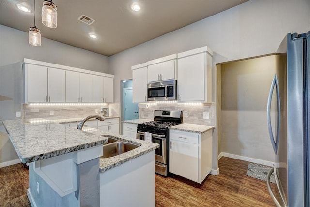 kitchen featuring visible vents, light stone countertops, a sink, appliances with stainless steel finishes, and hanging light fixtures