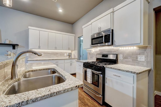 kitchen featuring a sink, appliances with stainless steel finishes, white cabinets, and light stone countertops