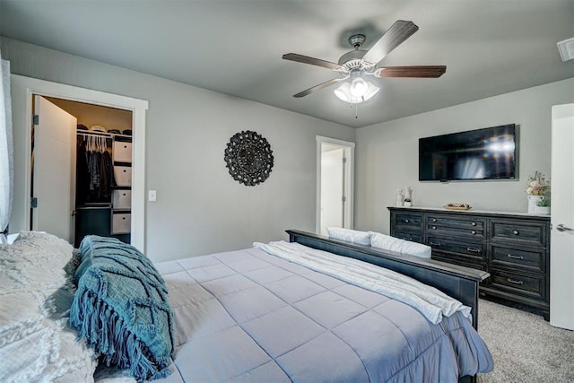bedroom with visible vents, a closet, light carpet, a walk in closet, and ceiling fan