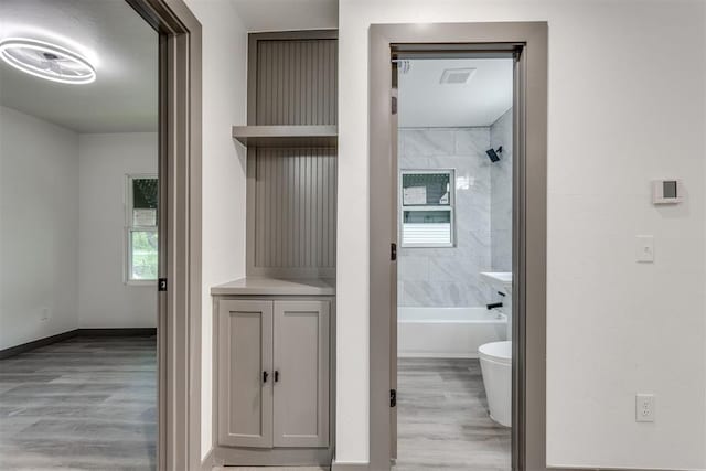 full bathroom featuring visible vents, bathtub / shower combination, wood finished floors, baseboards, and toilet