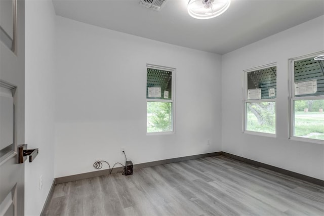 spare room with baseboards, visible vents, a wealth of natural light, and wood finished floors