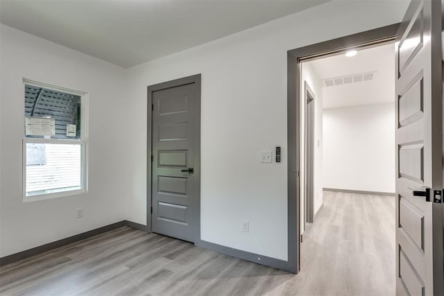 unfurnished bedroom featuring baseboards, visible vents, and light wood-style floors