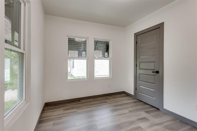 spare room with a healthy amount of sunlight, baseboards, and light wood-style flooring