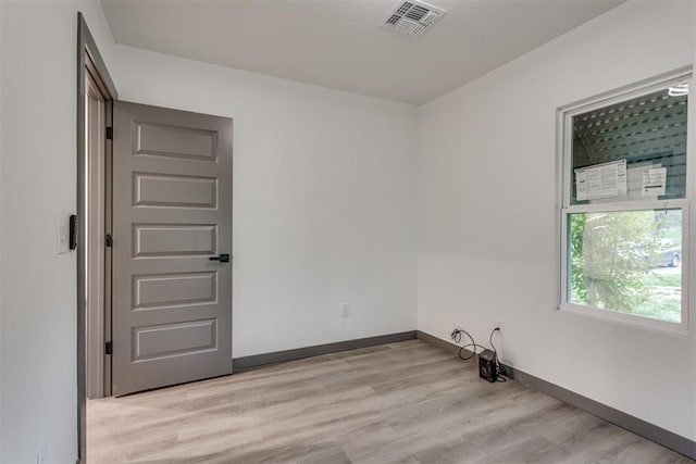 spare room with baseboards, light wood-style flooring, and visible vents
