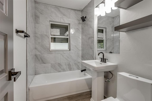 bathroom with toilet, washtub / shower combination, and wood finished floors