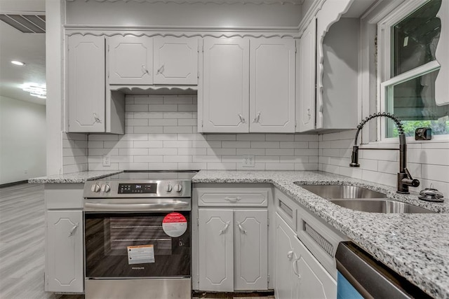 kitchen featuring a sink, appliances with stainless steel finishes, white cabinets, and backsplash