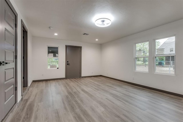 empty room featuring light wood-style floors, recessed lighting, baseboards, and visible vents
