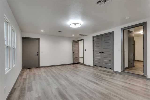 unfurnished bedroom with visible vents, light wood-style floors, and baseboards