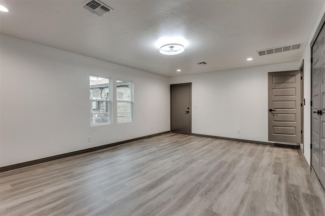 unfurnished room with light wood-style floors, baseboards, recessed lighting, and visible vents