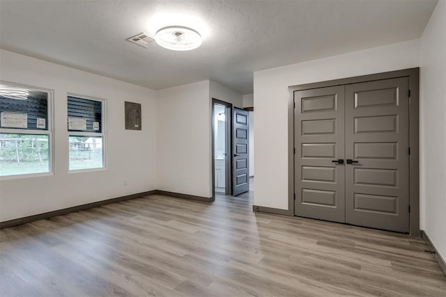 spare room featuring baseboards, light wood-type flooring, a textured ceiling, and visible vents