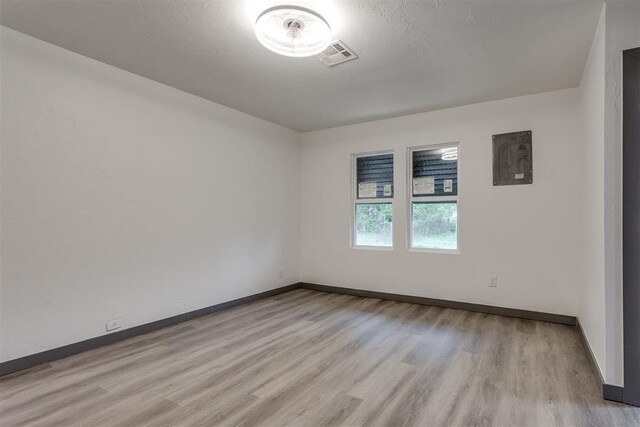 empty room featuring light wood-style floors, baseboards, and visible vents