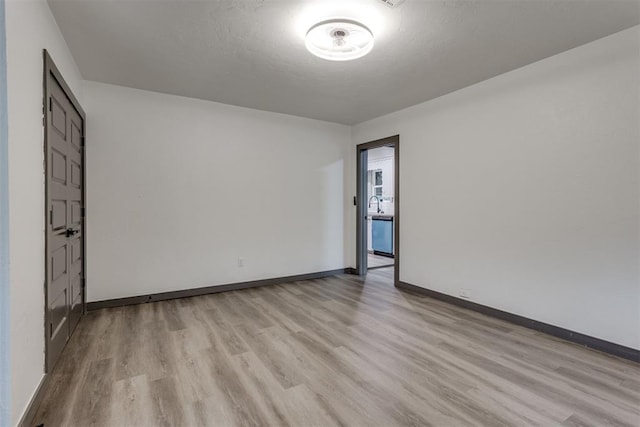 unfurnished room with baseboards, a sink, and wood finished floors
