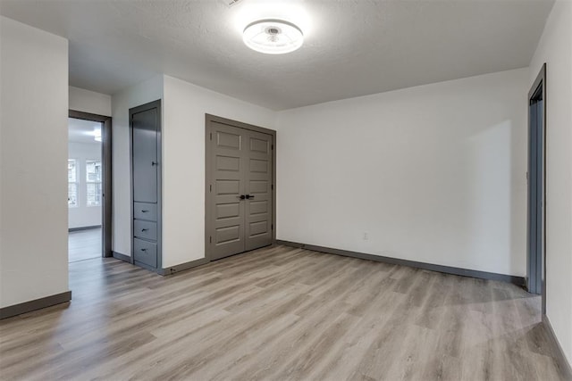 unfurnished bedroom featuring baseboards, light wood-style flooring, and a closet