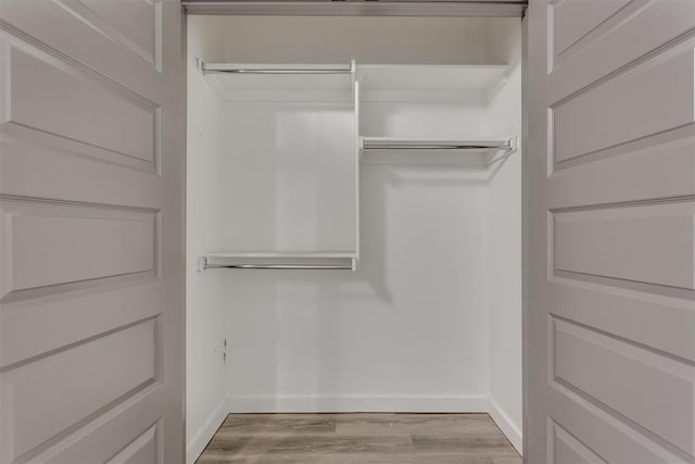 walk in closet with wood finished floors