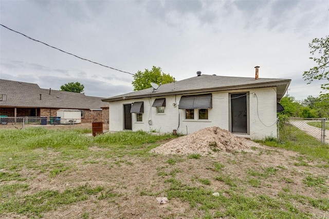 rear view of property featuring fence and brick siding
