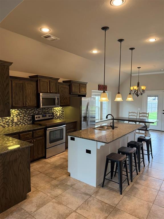 kitchen with backsplash, a kitchen bar, visible vents, appliances with stainless steel finishes, and a sink