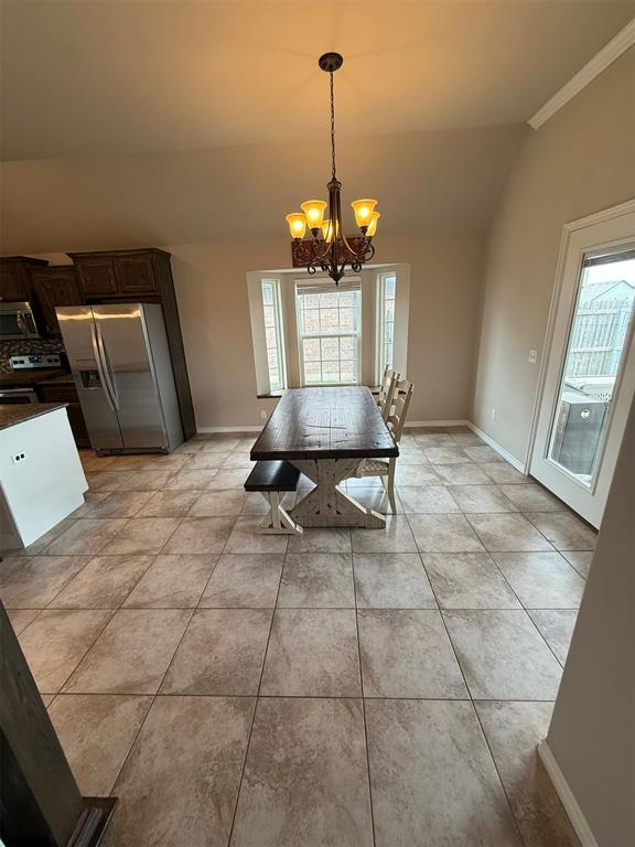 dining space with light tile patterned floors, baseboards, lofted ceiling, and a chandelier