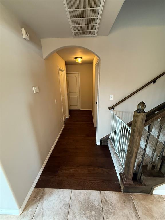 hall featuring arched walkways, baseboards, wood finished floors, visible vents, and stairway