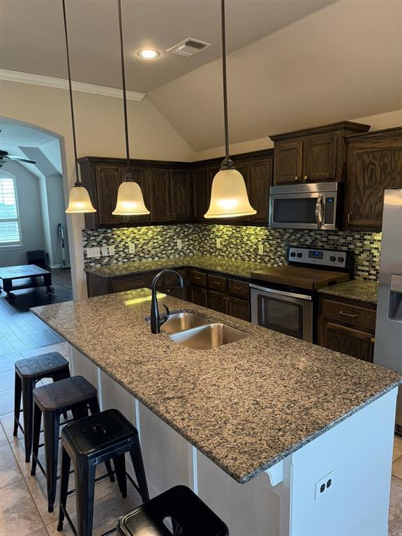 kitchen featuring dark brown cabinetry, a kitchen island with sink, visible vents, appliances with stainless steel finishes, and a sink