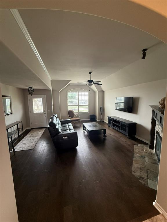 living room with baseboards, ceiling fan, wood finished floors, and lofted ceiling