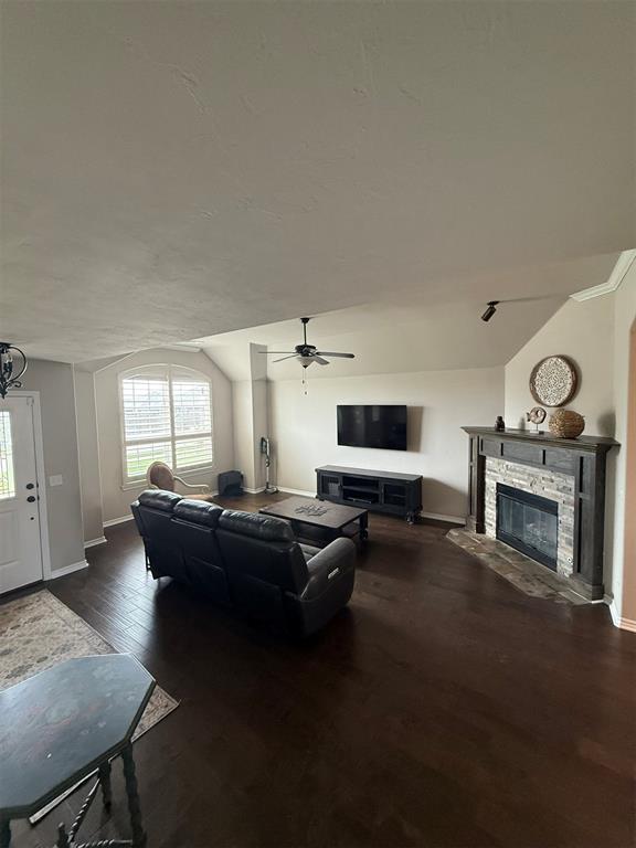 living area featuring a fireplace, a ceiling fan, baseboards, wood finished floors, and lofted ceiling