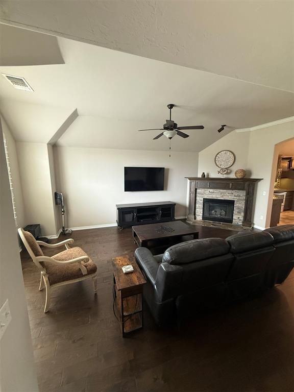 living room featuring a ceiling fan, visible vents, a fireplace, wood finished floors, and baseboards