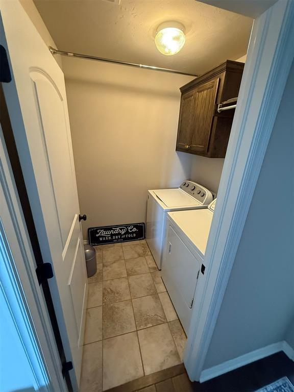 laundry area with cabinet space, light tile patterned flooring, and washing machine and clothes dryer