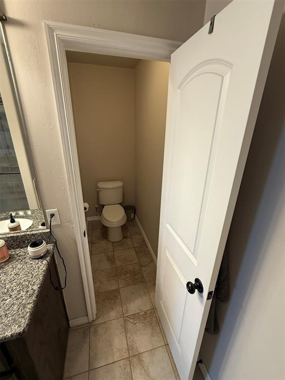 bathroom with vanity, tile patterned flooring, baseboards, and toilet