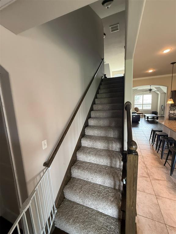 stairs featuring a ceiling fan, visible vents, crown molding, tile patterned flooring, and recessed lighting