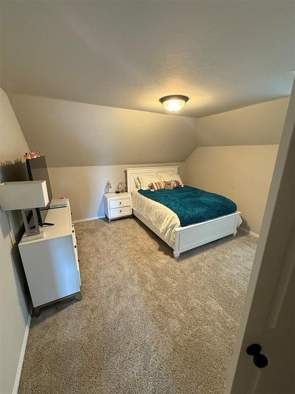carpeted bedroom featuring baseboards and lofted ceiling