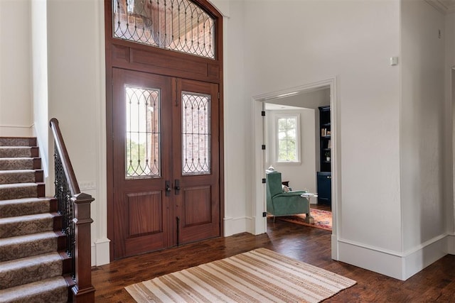foyer with stairs, wood finished floors, a high ceiling, and baseboards