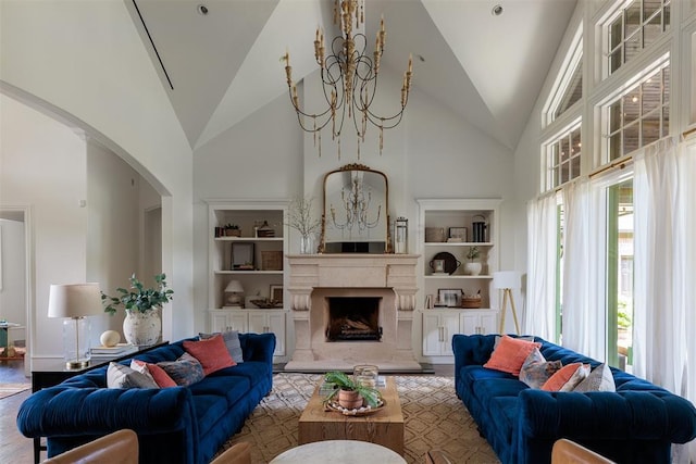 living room with a chandelier, arched walkways, built in features, high vaulted ceiling, and a fireplace