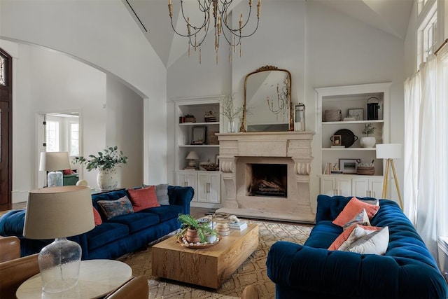 living area with high vaulted ceiling, arched walkways, built in shelves, a chandelier, and a fireplace