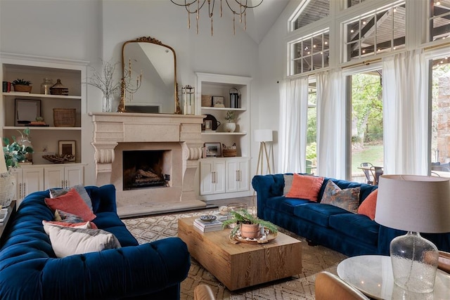 living area with built in features, a chandelier, a high end fireplace, and high vaulted ceiling